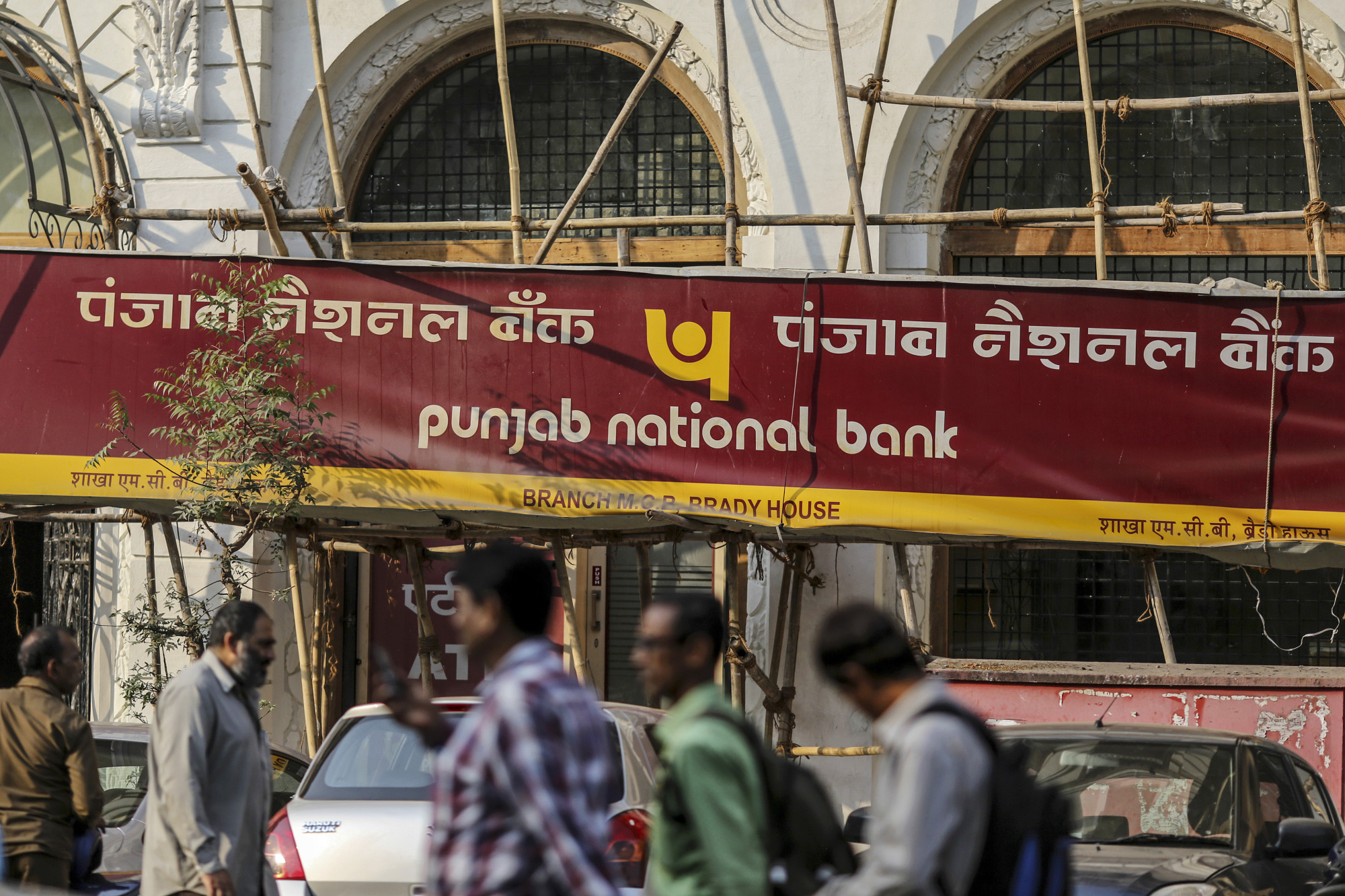 Pedestrians walk past a Punjab National Bank (PNB) branch in Mumbai.