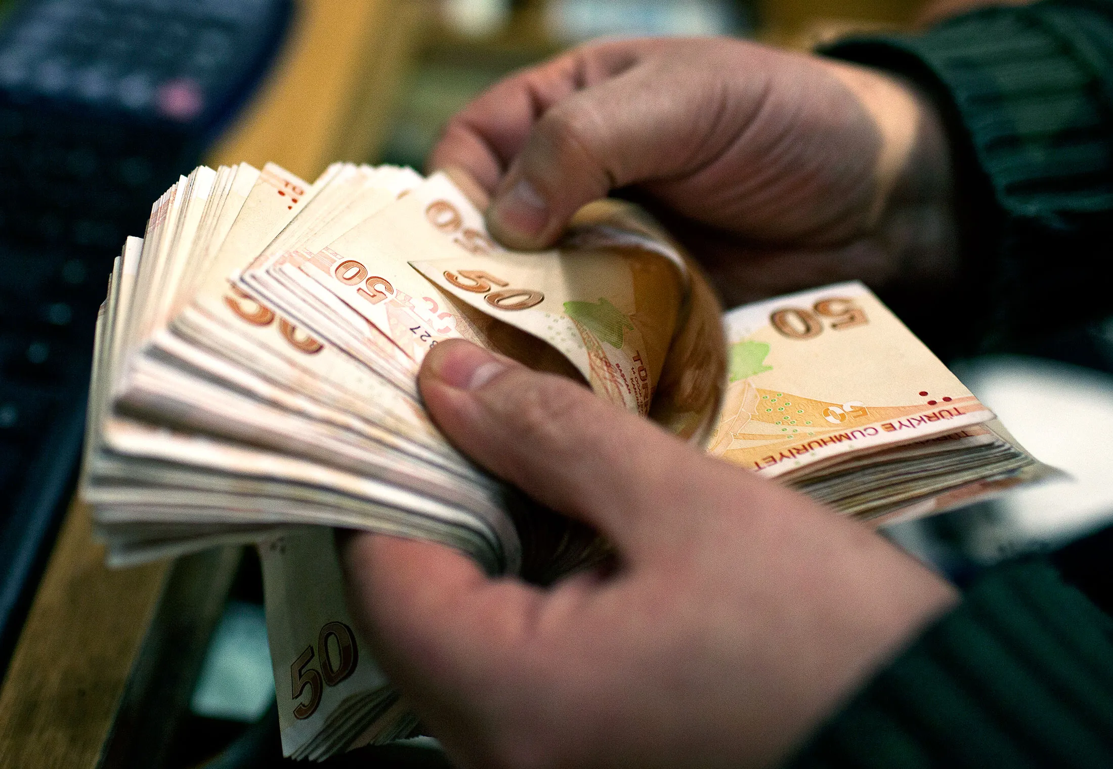 An employee counts out 50 Turkish lira banknotes at a currency exchange office in Istanbul.

