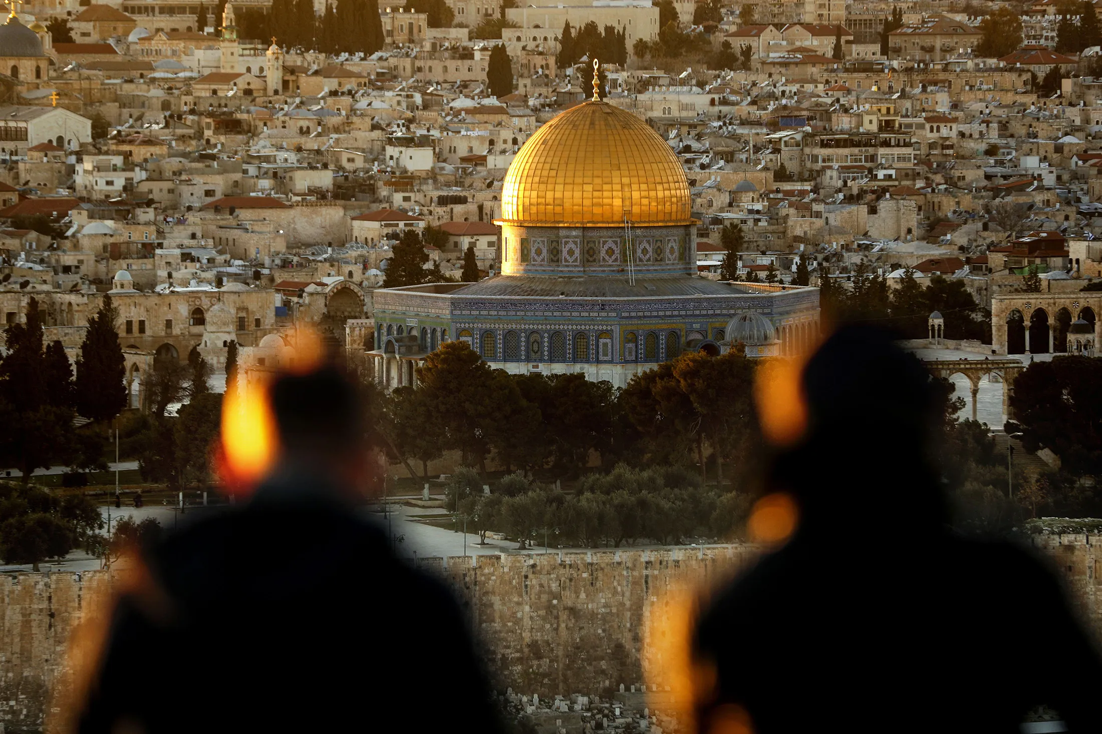 Two persons watch the sun setting on the Old City of Jerusalem, with the Muslim mosque of the Dome of the Rock in the center, on Jan.&nbsp;23, 2017.&nbsp;