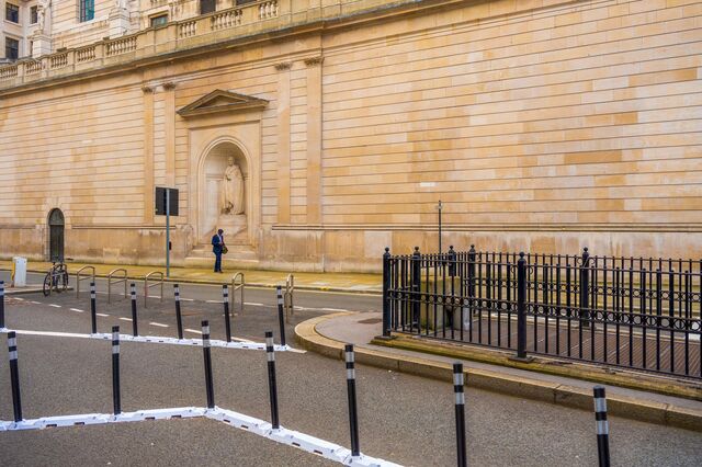 A commuter walks checking his phone alongside the Bank of England in the City of London, U.K., on Thursday, July 1, 2021. With the vast majority of the Square Mile’s 500,000 office staff working from home during the pandemic, once-bustling streets have been largely deserted.