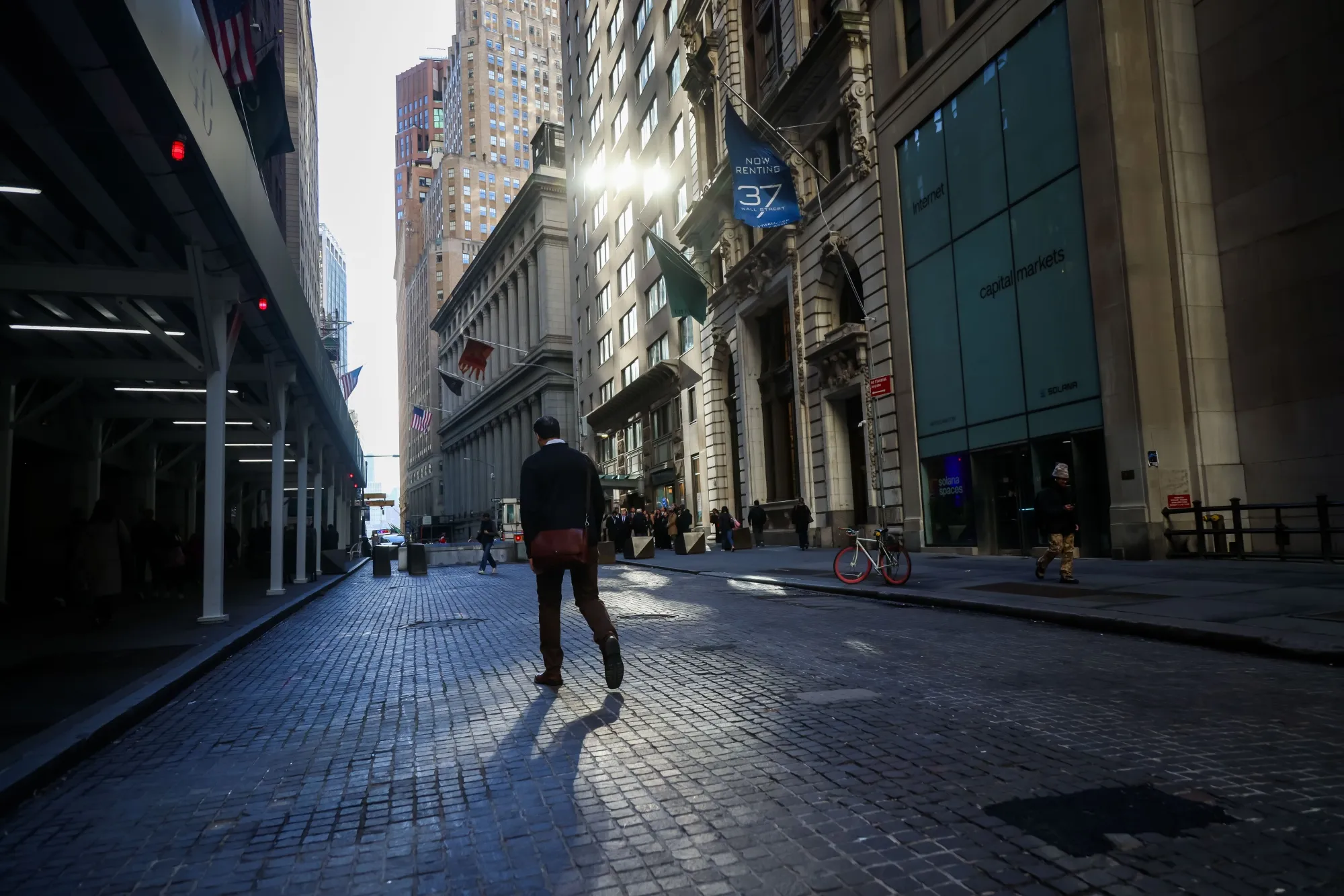 Pedestrians walk along Wall Street, near the New York Stock Exchange (NYSE) in New York.