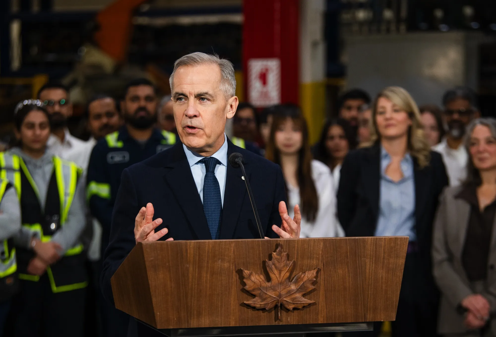 Canada's Industry Minister Melanie Joly, right, listens as Canada’s Prime Minister&nbsp;Mark Carney&nbsp;speaks at a Martinrea auto parts manufacturing facility in Woodbridge, Ontario on Feb. 5.