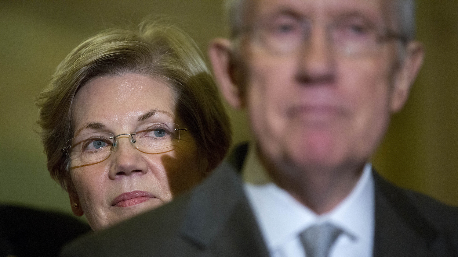 Senator Elizabeth Warren, a Democrat from Massachusetts, left, looks on as Senate Majority Leader Harry Reid, a Democrat from Nevada, speaks during a news conference following a private meeting at the U.S. Capitol Building in Washington, D.C., U.S., on Thursday, Nov. 13, 2014.
