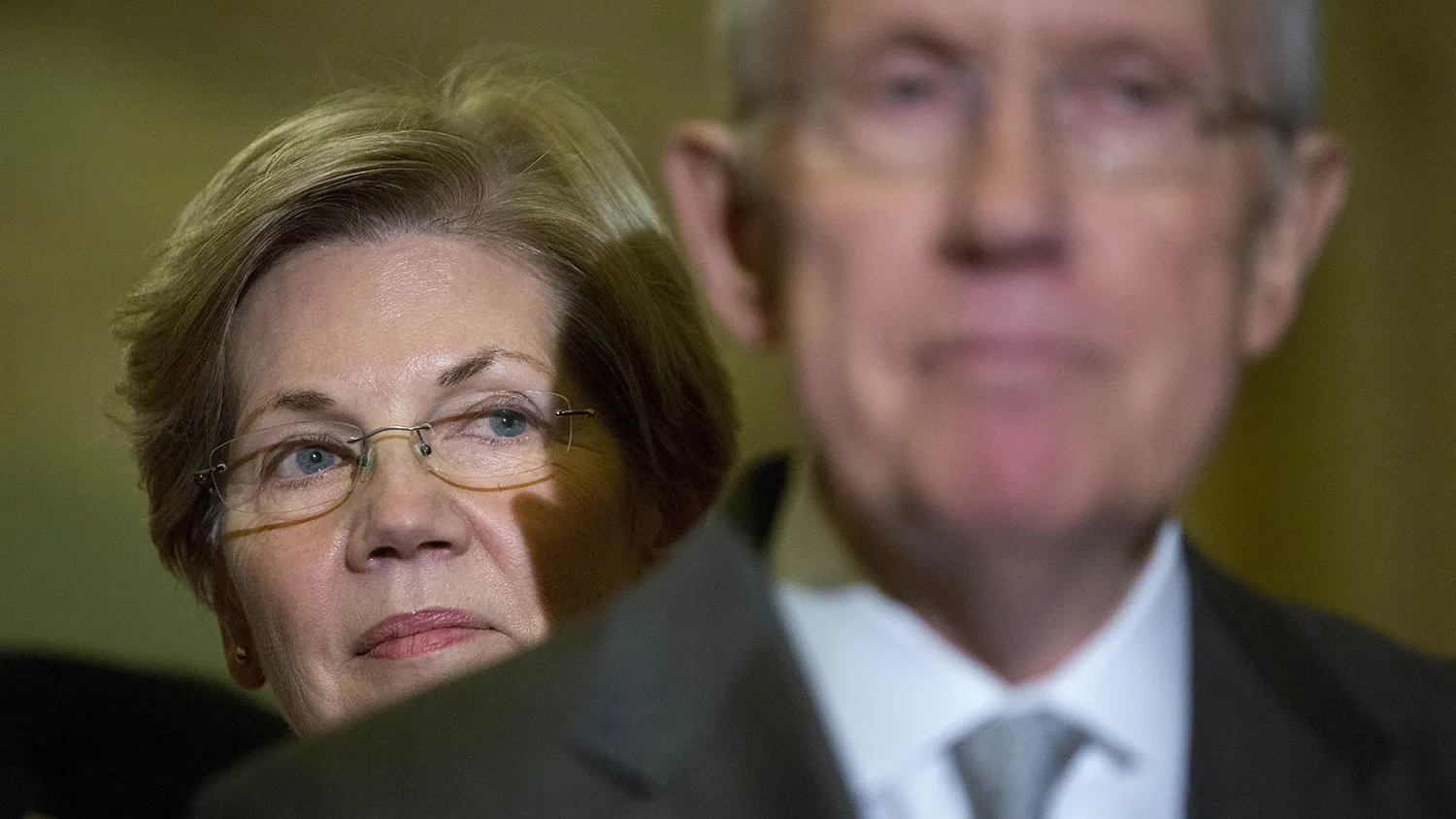 Senator Elizabeth Warren, a Democrat from Massachusetts, left, looks on as Senate Majority Leader Harry Reid, a Democrat from Nevada, speaks during a news conference following a private meeting at the U.S. Capitol Building in Washington, D.C., U.S., on Thursday, Nov. 13, 2014.
