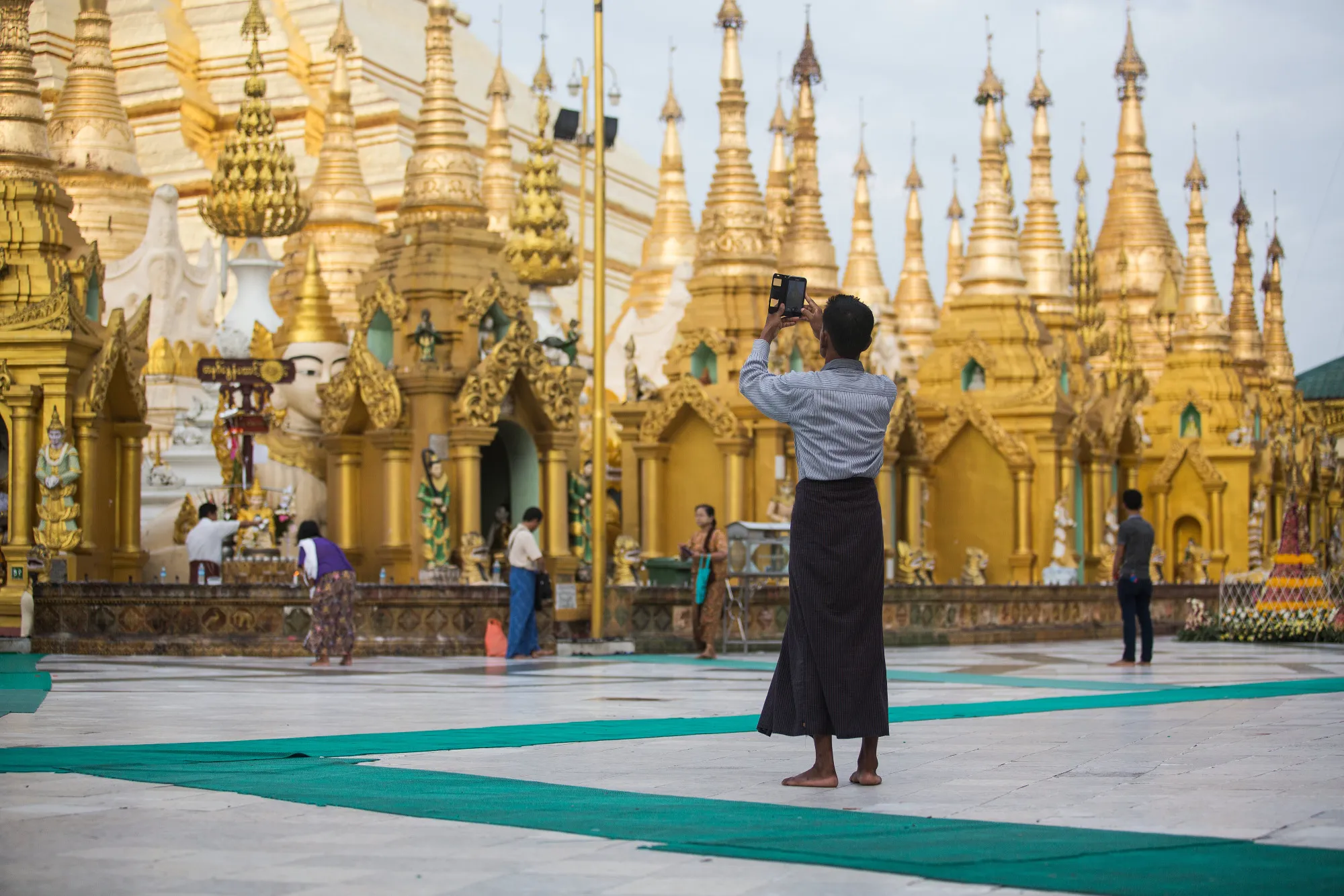 A visitor uses a smartphone to take a photograph at the Shwedagon Pagoda in Yangon, Myanmar.