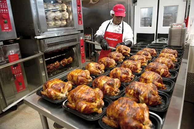 A service deli worker for Costco Wholesale Corp. places cooked rotisserie chickens in containers at a store in San Francisco