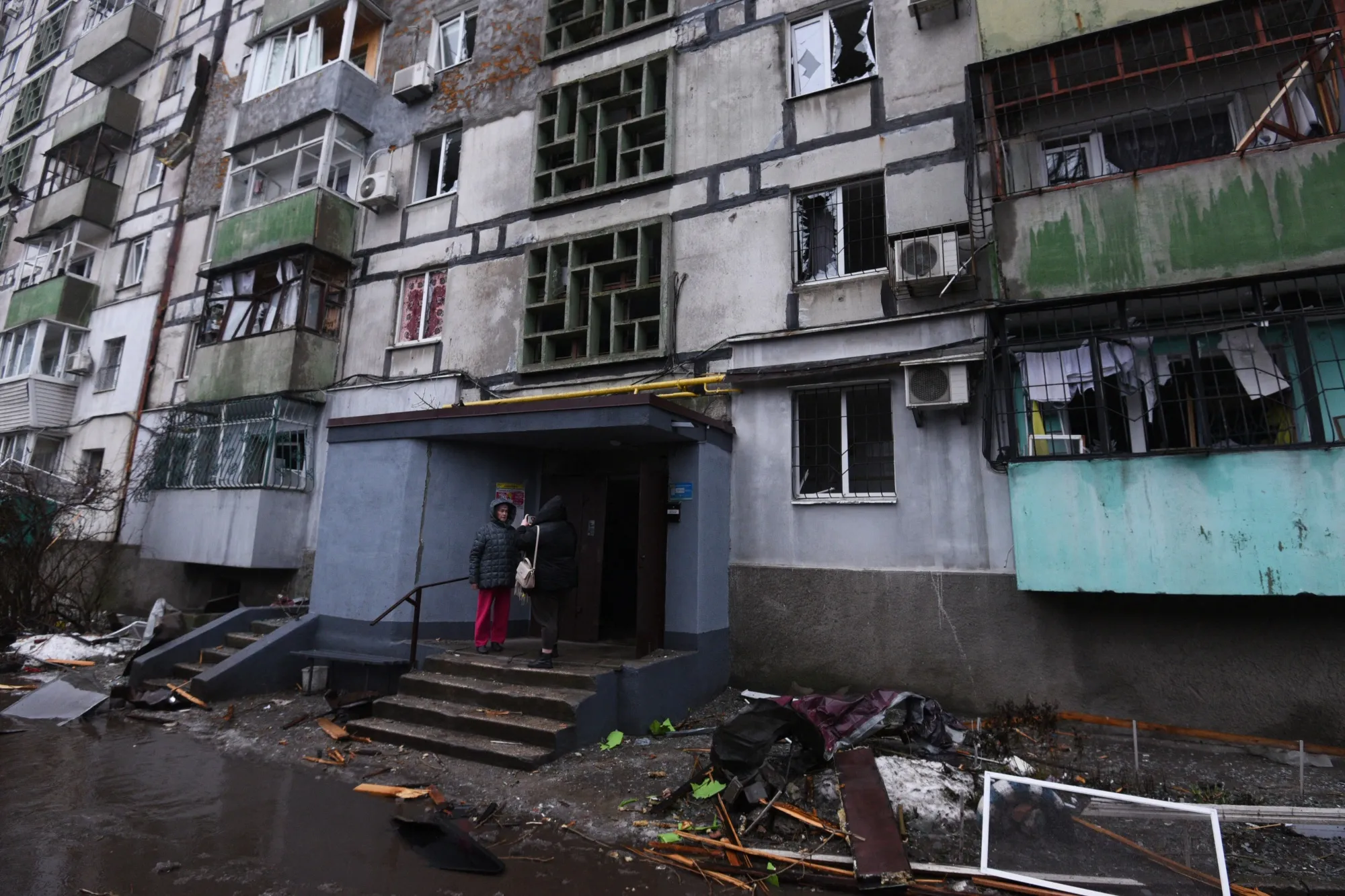 Local residents stand on the porch of a damaged residential building following a Russian drone attack in Dnipro, Ukraine on Jan. 7, 2026.
