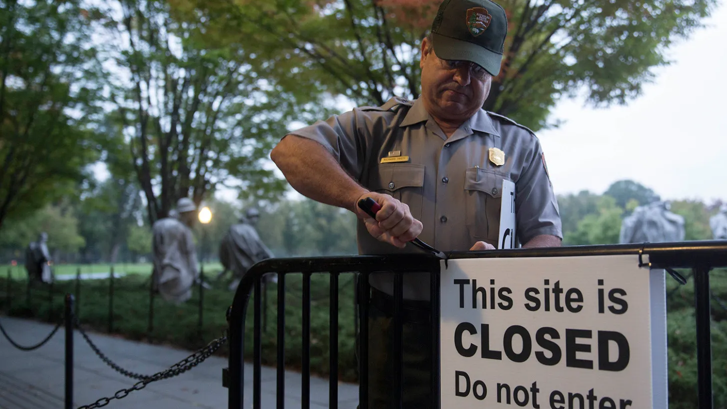 National Park Service park ranger Richard Trott removes a closed sign at the Korean War Veterans Memorial in Washington, D.C., U.S., on Thursday, Oct. 17, 2013.
