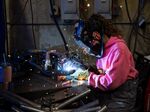 A worker welds together bumpers for three-wheeled electric vehicles at a facility in Eugene, Oregon.