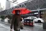 A pedestrian&nbsp;wearing a protective mask and carrying an umbrella walks near Port Authority Bus Terminal in New York on May 8.