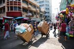 Workers carry boxes on trolleys past stalls at a Market in Manila.