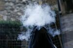 A pedestrian stands in a cloud of vapour after exhaling from an e-cigarette.