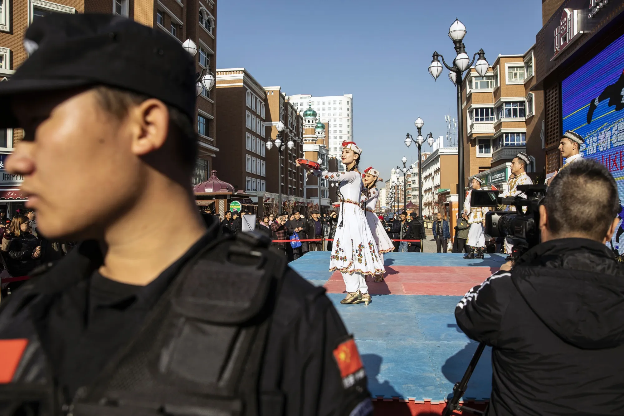 A security officer keeps watch as women perform a traditional dance at the main bazaar of Xinjiang’s regional capital, Urumqi, in November.