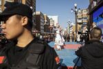 A security officer keeps watch as women perform a traditional dance at the main bazaar of Xinjiang’s regional capital, Urumqi, in November.