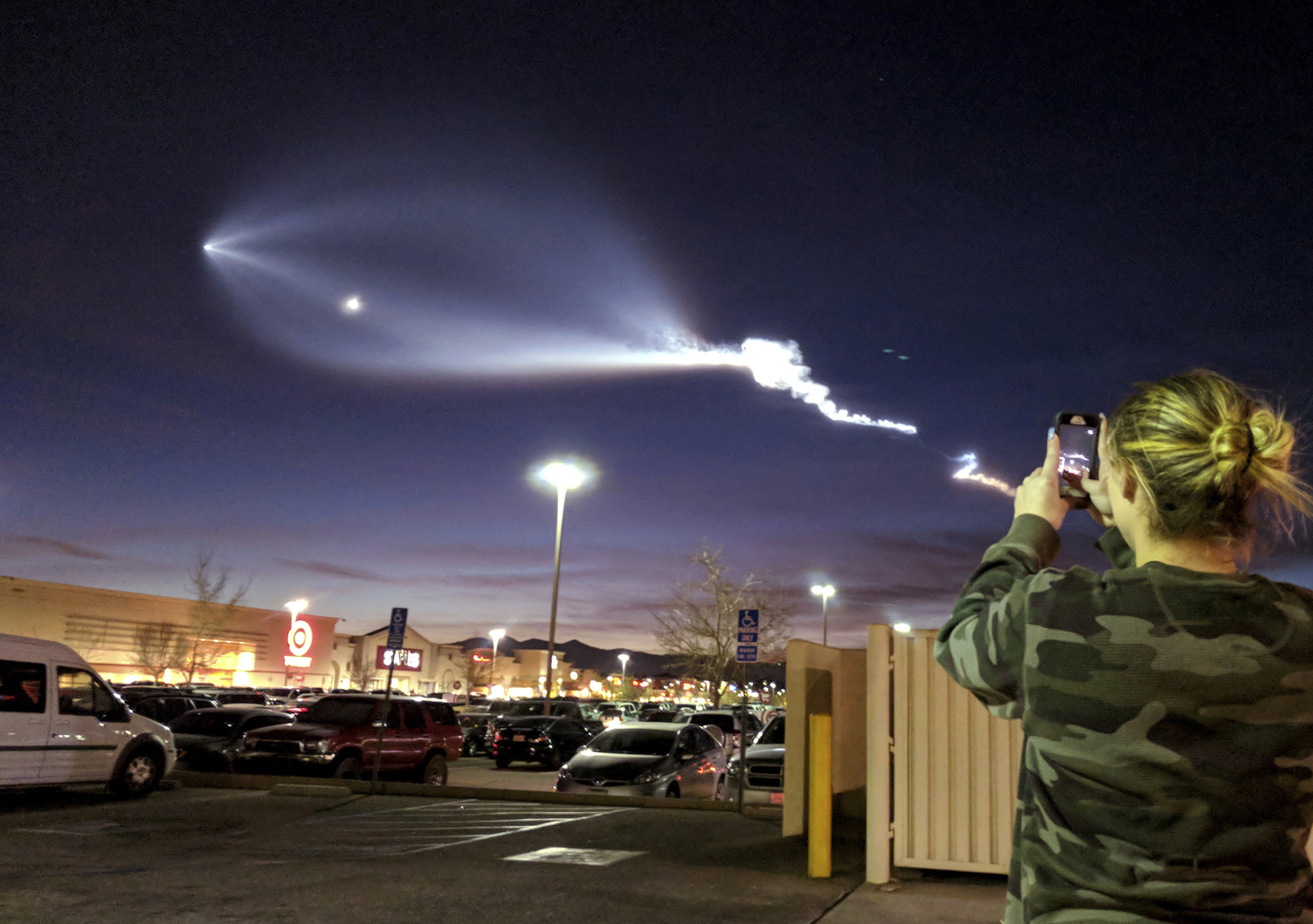 A woman photographs the light display of SpaceX's Falcon 9 rocket launch.&nbsp;