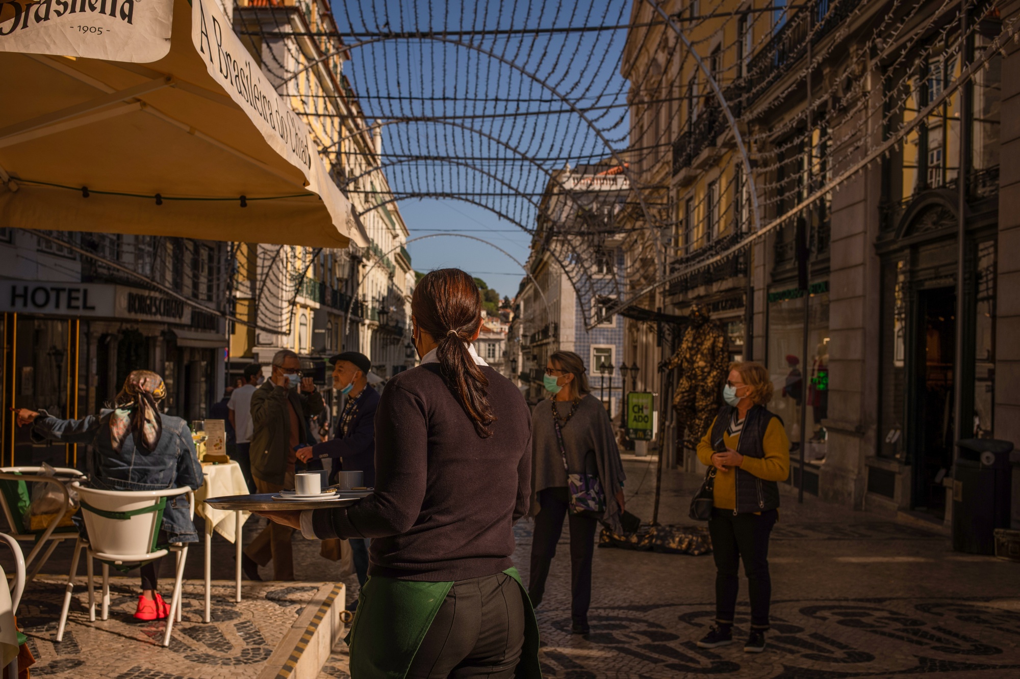 Funcionário atende clientes na esplanada de um hotel do bairro do Shiado, em Lisboa.