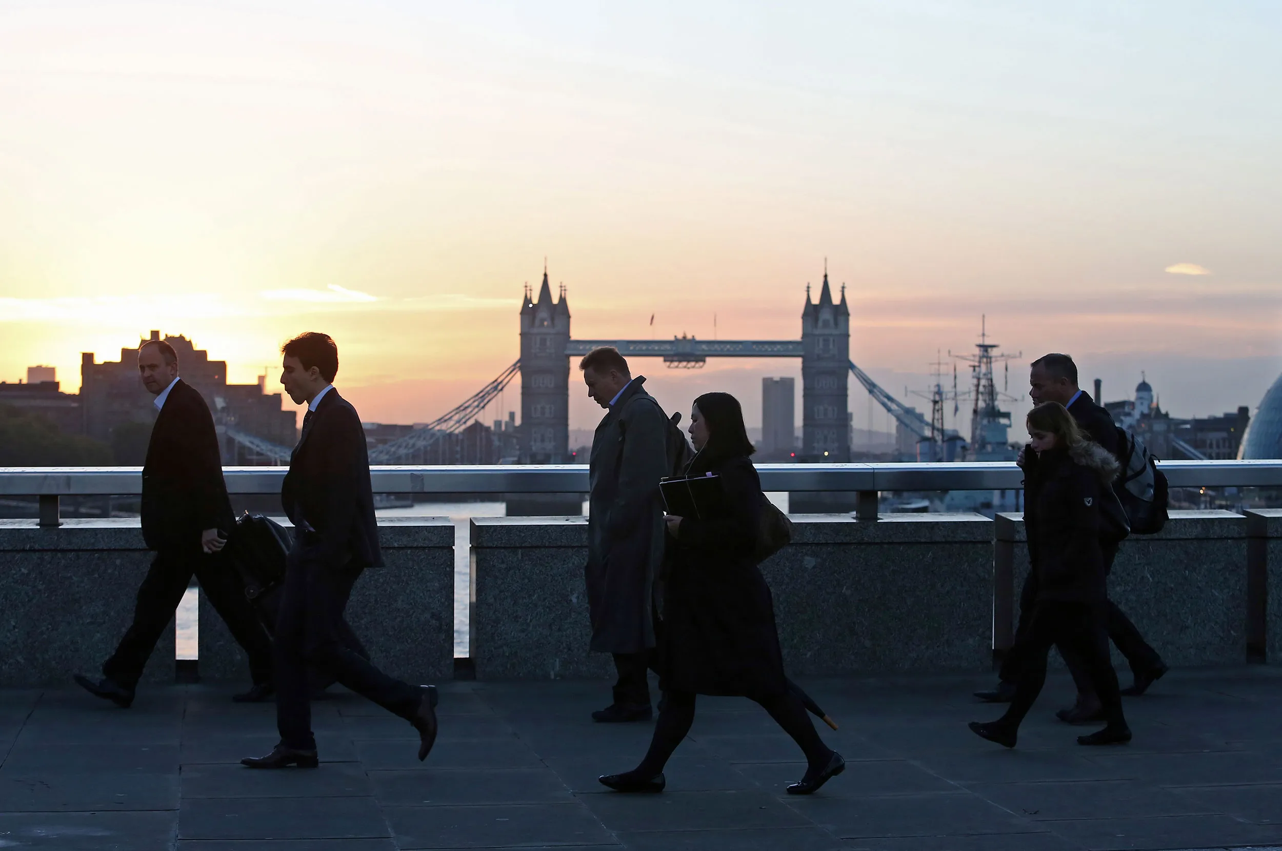 Commuters cross London Bridge towards the City of London financial district.
