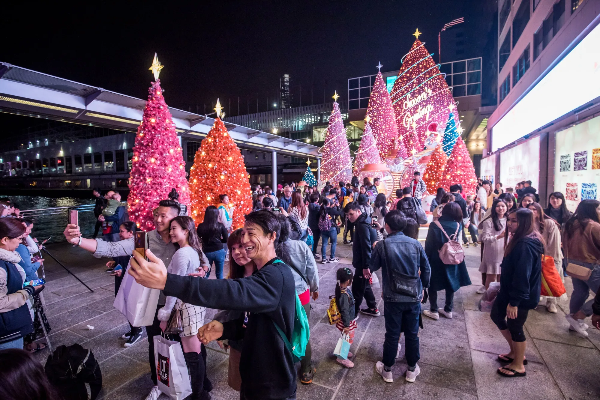 People pose for photographs with festive Christmas decorations near an entrance to Harbour City shopping mall&nbsp;in Tsim Sha Tsui.