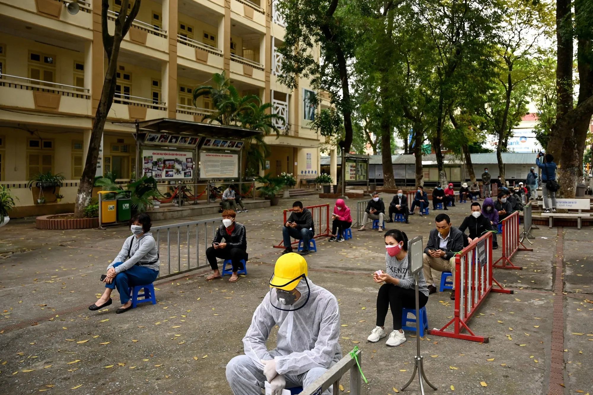 Residents practice social distancing as they wait to be tested at a makeshift rapid testing center near Bach Mai hospital in Hanoi, on March 31.