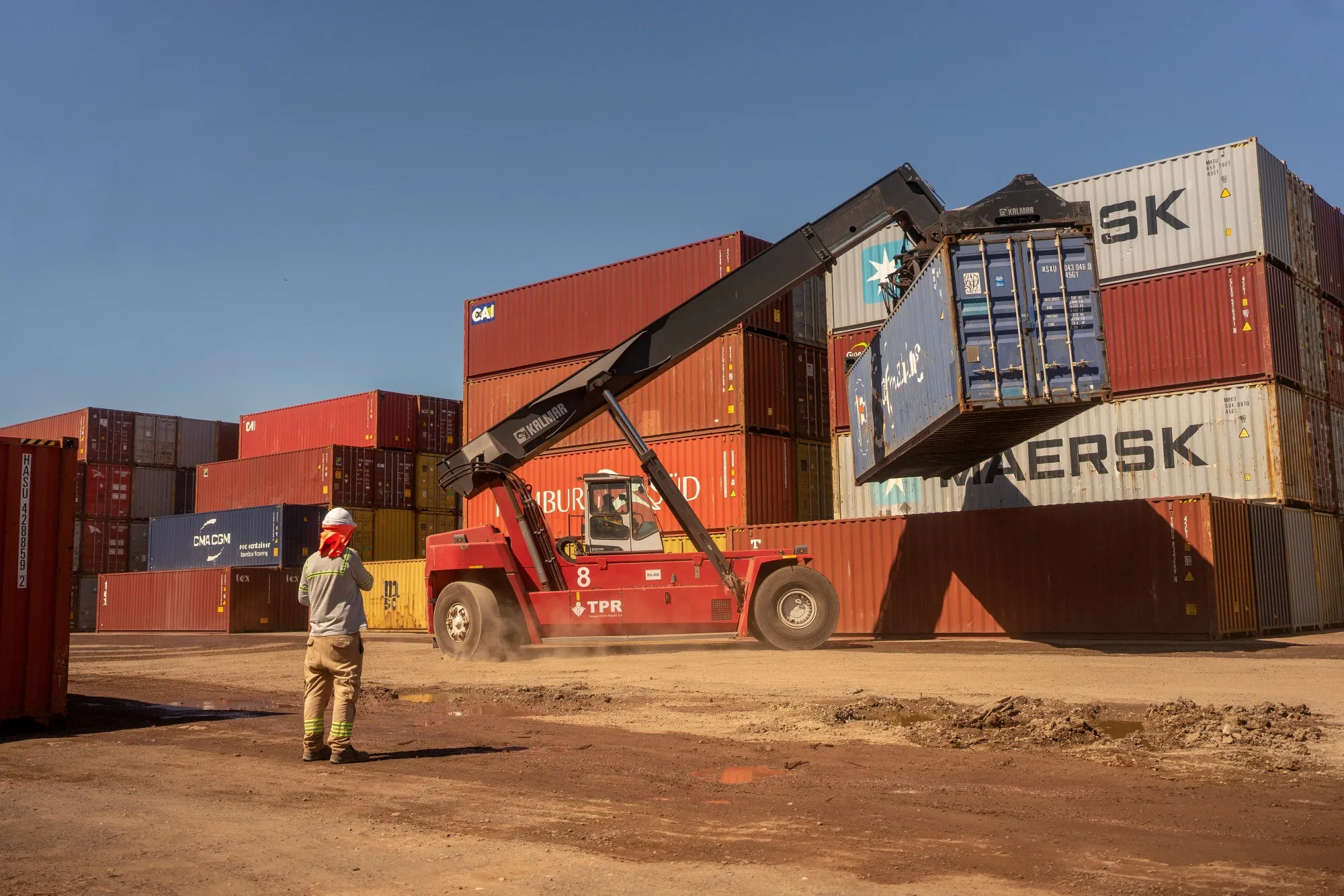 A worker watches as shipping containers are unloaded at the Port of Rosario in Rosario, Argentina.