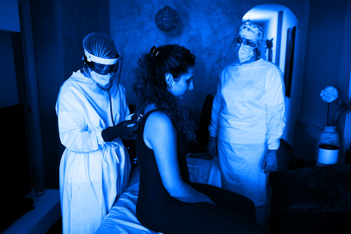 Woman being examined by two health care workers for symptoms related to Covid-19