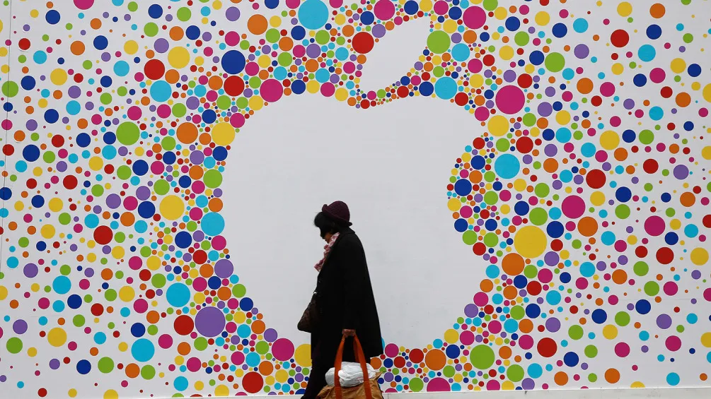 A pedestrian carries a shopping bag as she passes a giant Apple Inc. logo outside a new Apple store, still under development, on Princess Street in Edinburgh, U.K., on Wednesday, Sept. 17, 2014.
