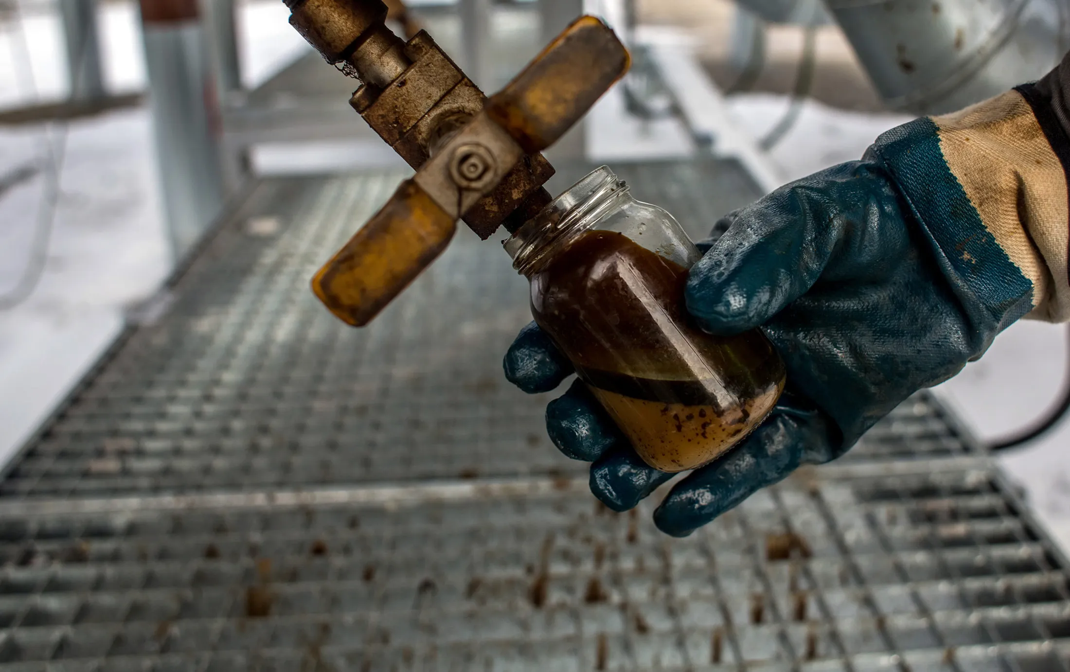 An employee collects an oil sample in a jar near the oil pumping machinery at a plant operated by Moravske Naftove Doly (MND) AS in Damborice, Czech Republic, on Friday, Jan. 8, 2016. Oil capped the biggest two-year loss on record in 2015 as the Organization of Petroleum Exporting Countries effectively abandoned output limits amid a global glut.
