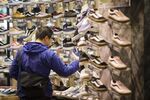 A shopper checks sneakers displayed for sale at a footwear store in the Odaiba area of Tokyo, Japan.