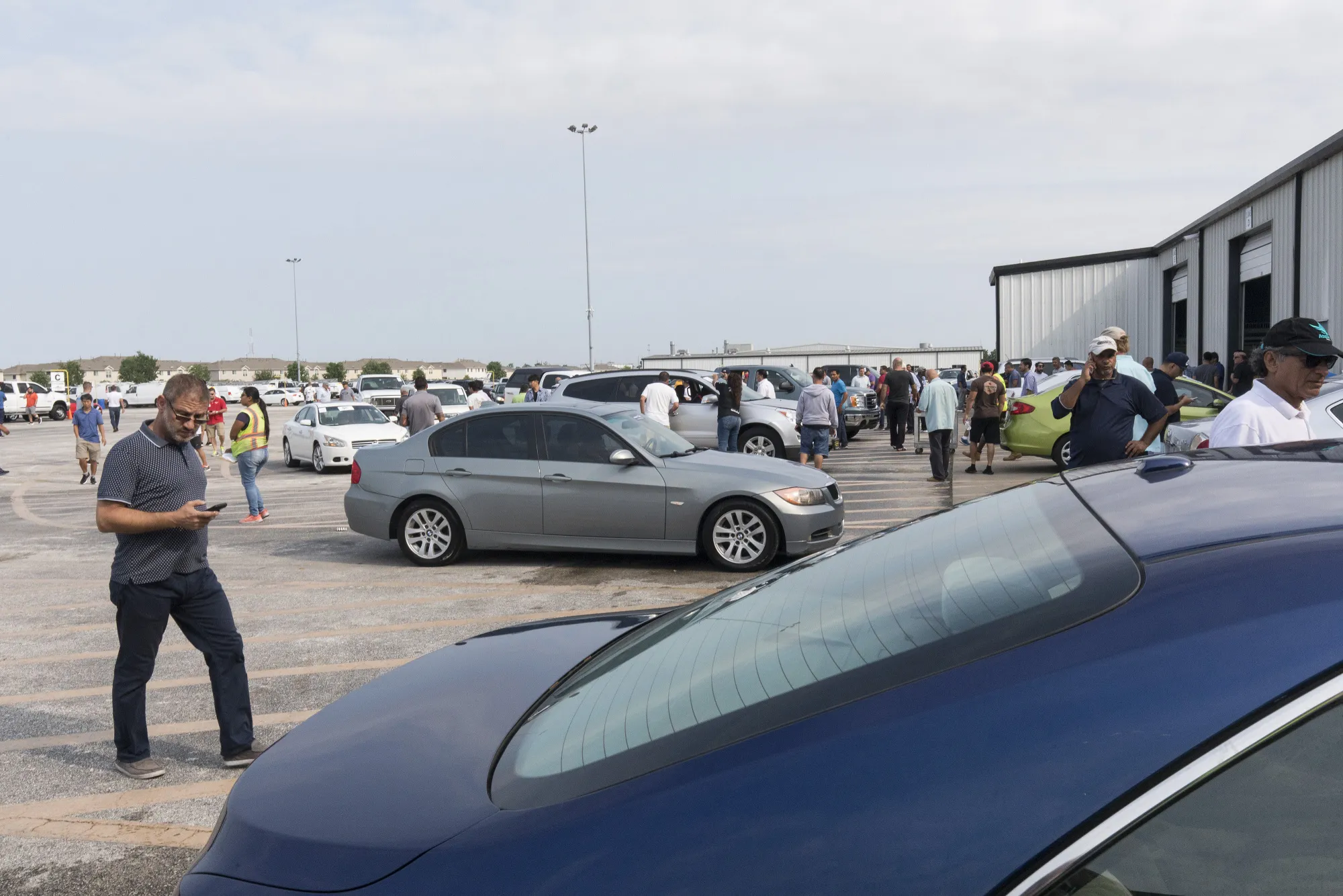 Buyers for car dealers view vehicles before an automobile auction at the Adesa facility, a unit of KAR Auction Services, in Houston.