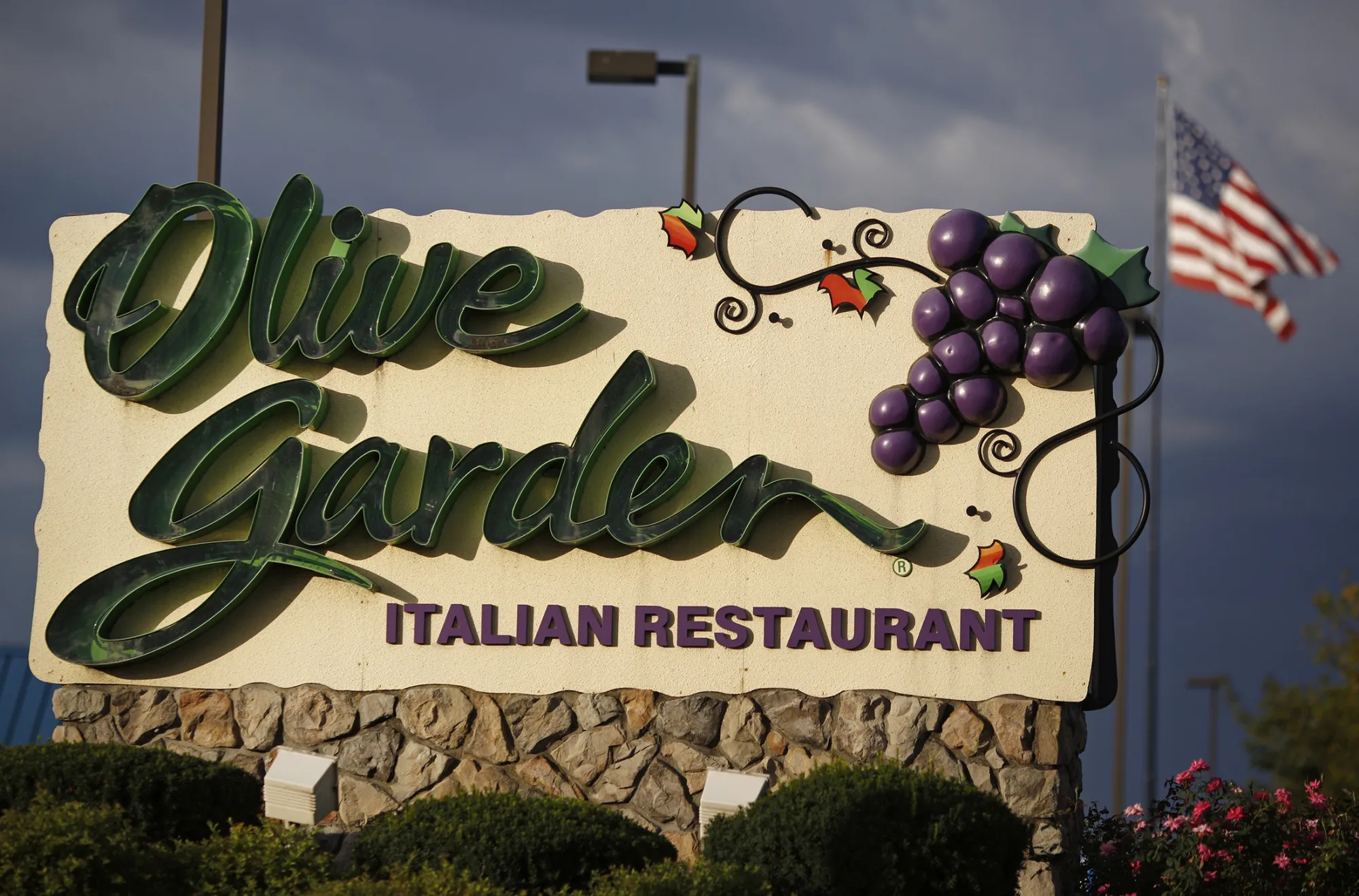 An American flag flies past a Darden Restaurants Inc. Olive Garden location in Clarksville, Indiana.