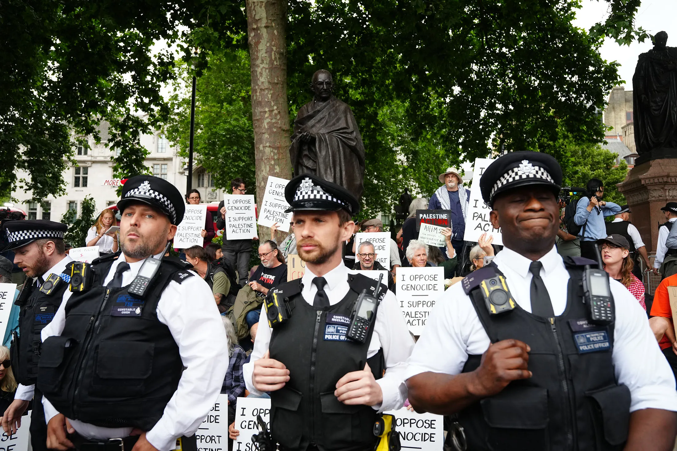 Metropolitan Police officers observe a protest in support of Palestine Action, organised by the Defend Our Juries group, in front of the Mahatma Gandhii statue in Parliament Square, London, on July 5.