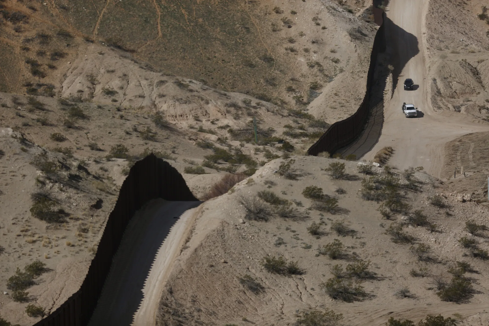 Vehicles drive past a section of a border fence that separates the U.S. and Mexico in Sunland Park, New Mexico.