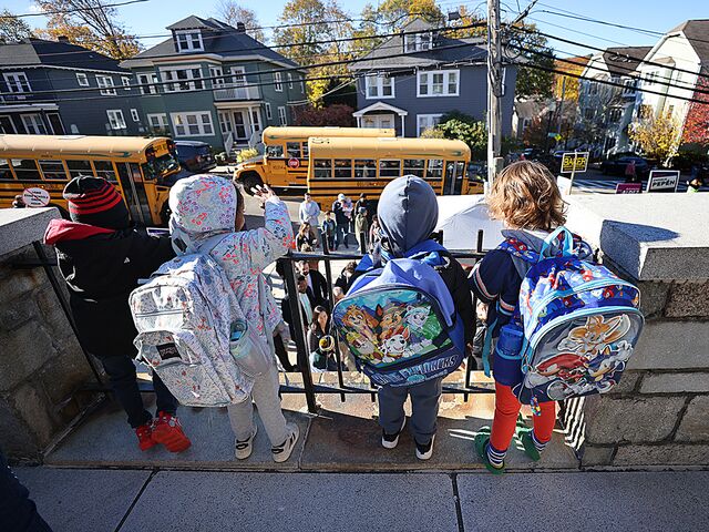Elementary school students wave at Michelle Wu