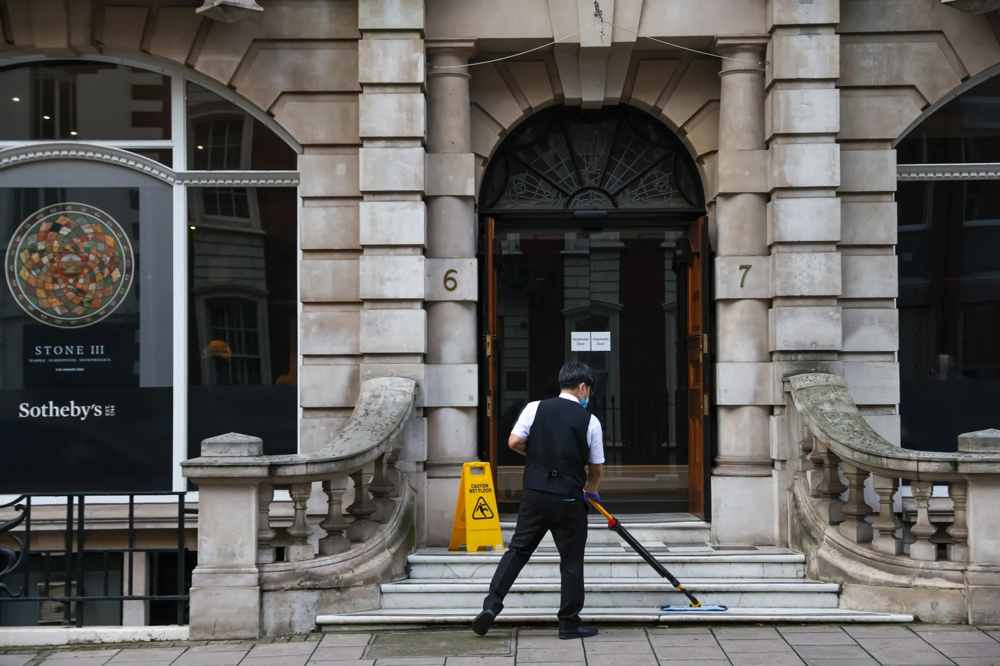 A worker mops the steps outside Sotheby's in Mayfair, London, U.K., on Tuesday, Jan. 4, 2022.