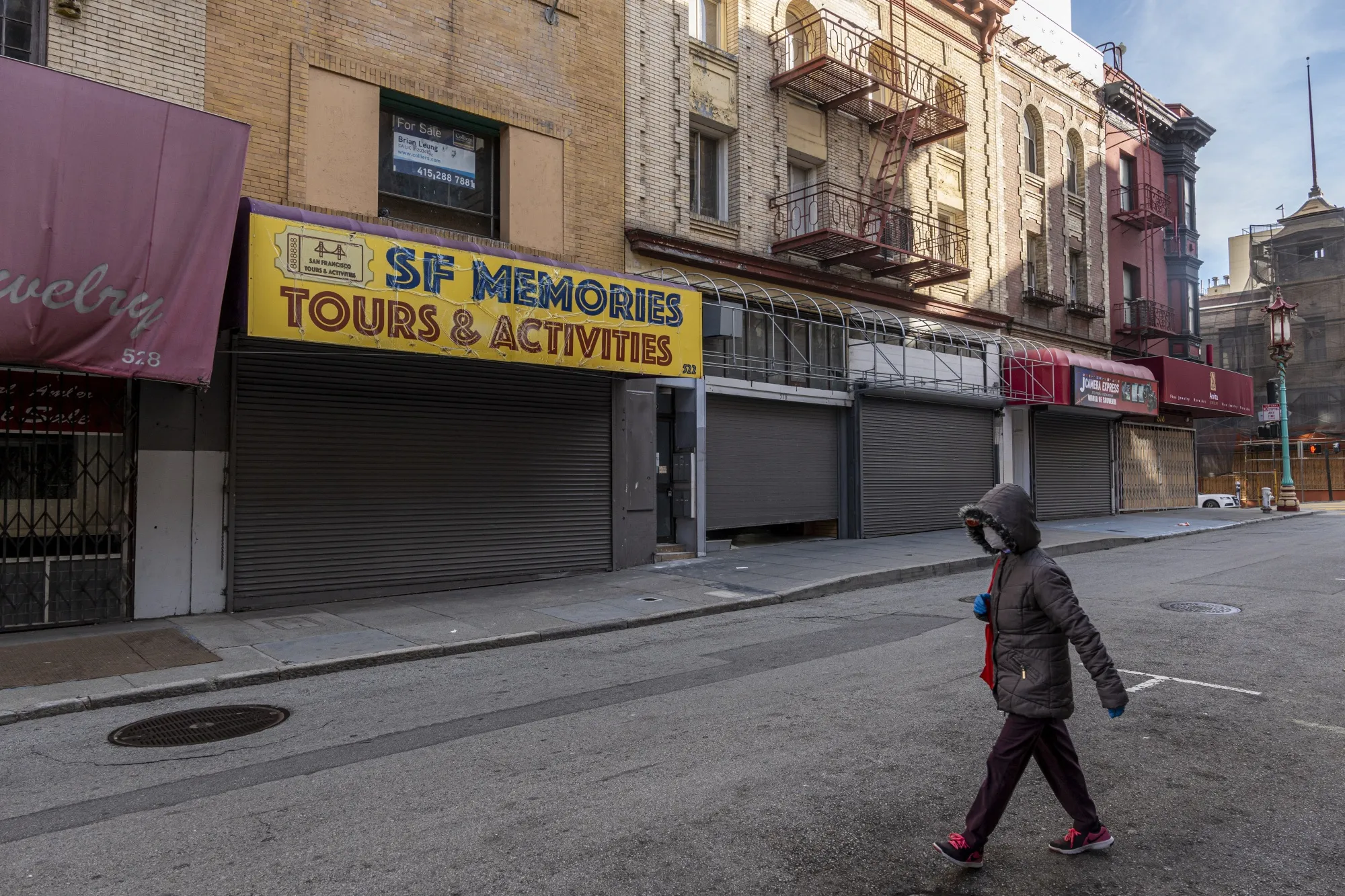A pedestrian wearing a protective mask walks past closed stores on Grant Avenue in San Francisco, on Dec. 29.