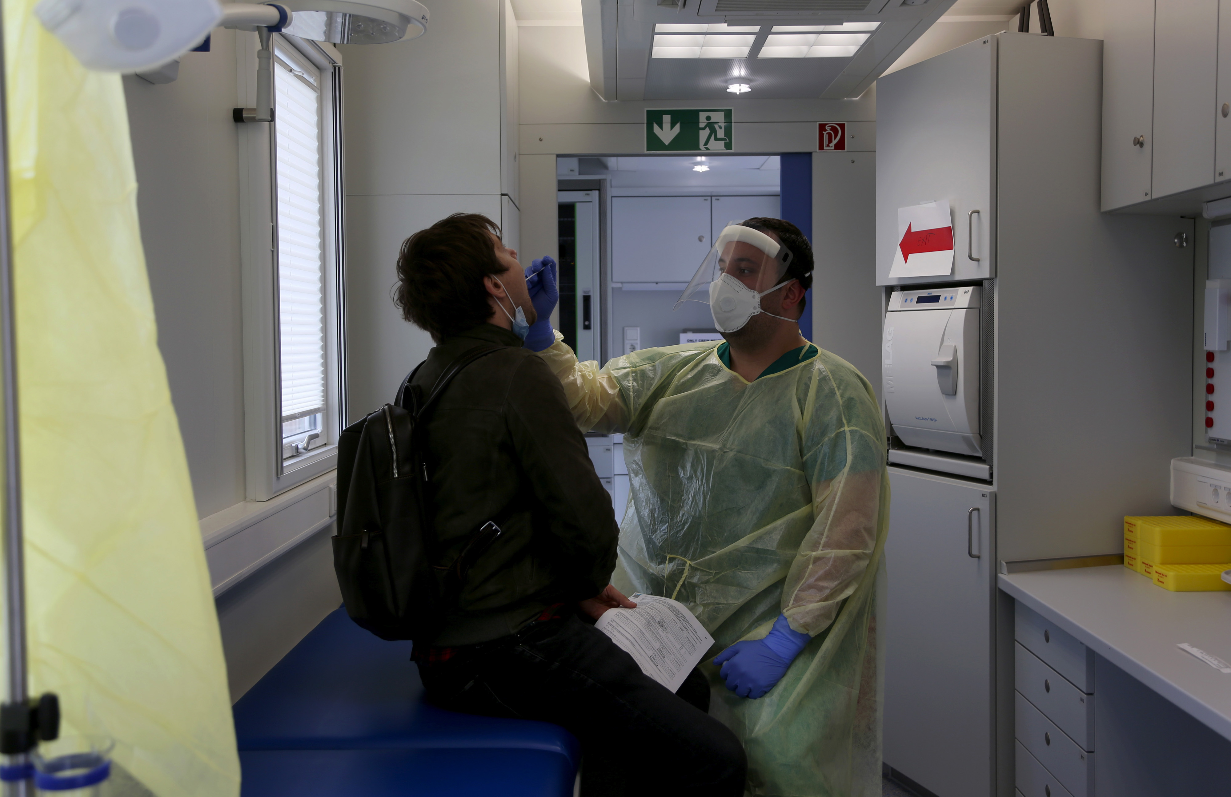A health worker administers a Covid-19 swab test on a traveler after arriving on a coach in Berlin, Oct. 12.