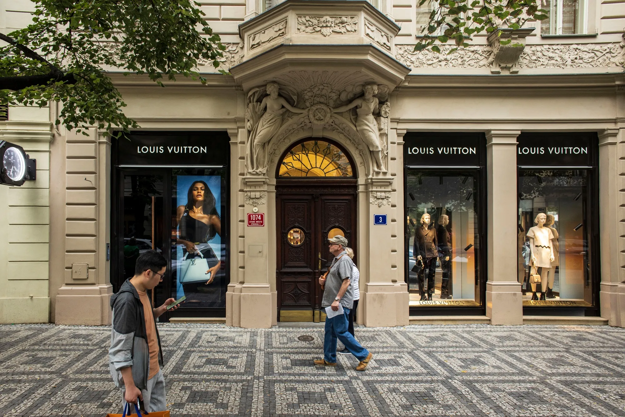 Pedestrians pass a Louis Vuitton luxury clothing boutique in Prague, Czech Republic.