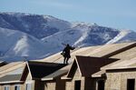 A worker installs roofing on an apartment complex under construction in Lehi, Utah.
