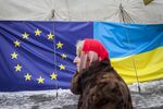 A woman walks past a tent displaying the European Union and Ukrainian flags in Independence Square in Kiev.