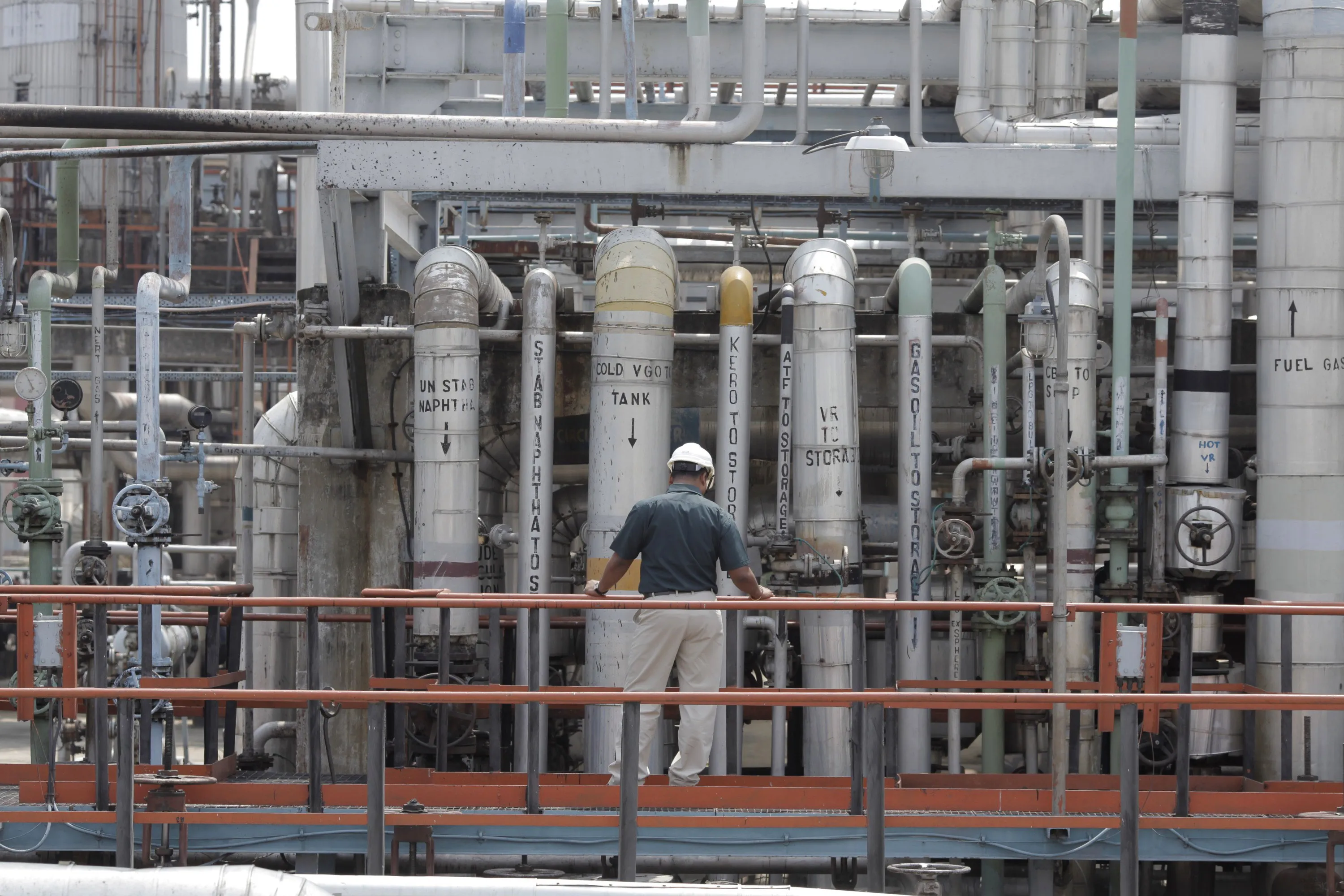 A worker inspects pipes carrying different fuel products at a refinery complex in Golaghat, India.