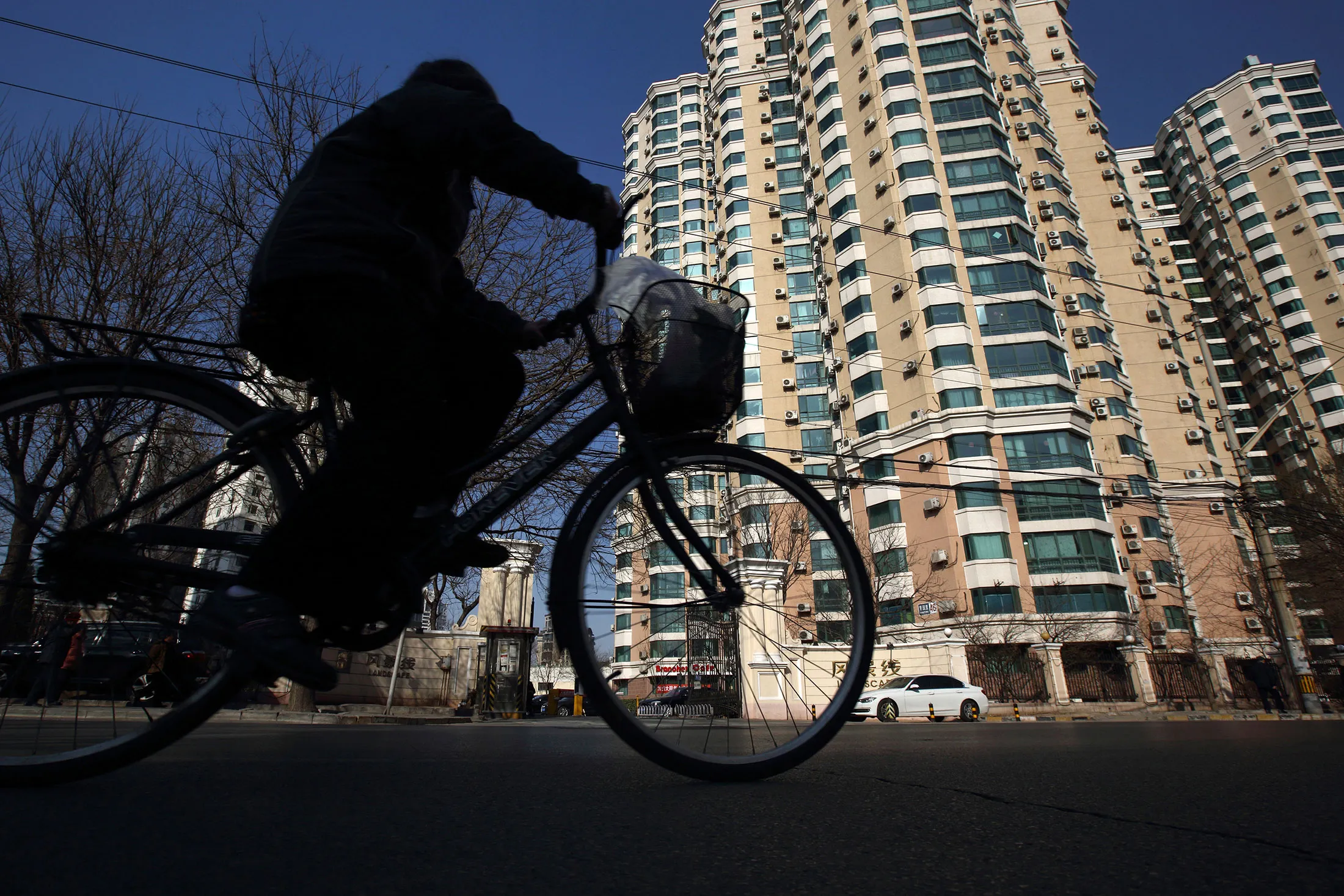 A man rides a bicycle past residential buildings in Beijing.
