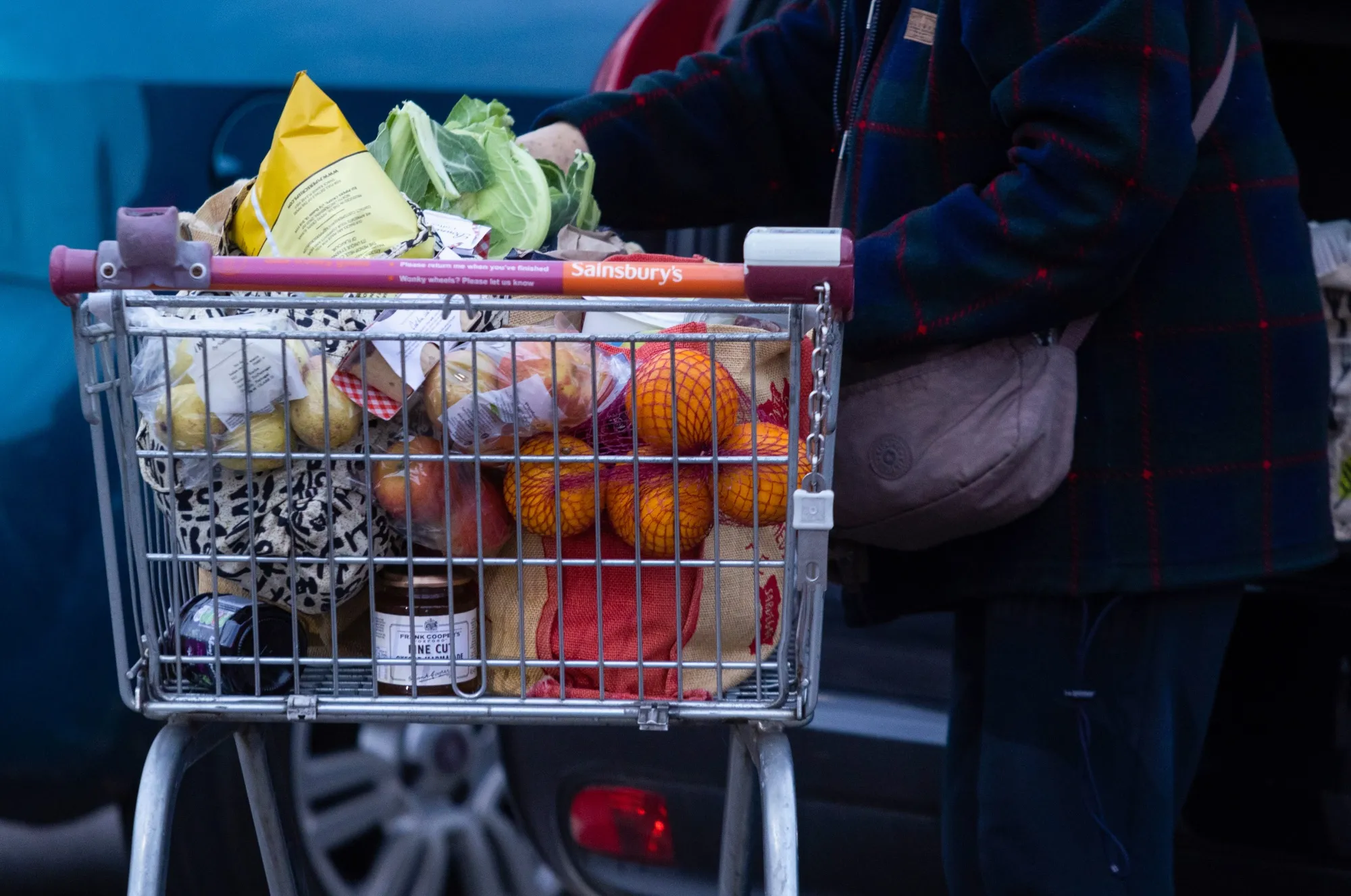 A customer empties her shopping trolley into her car outside a J Sainsbury Plc supermarket in Colney, UK.
