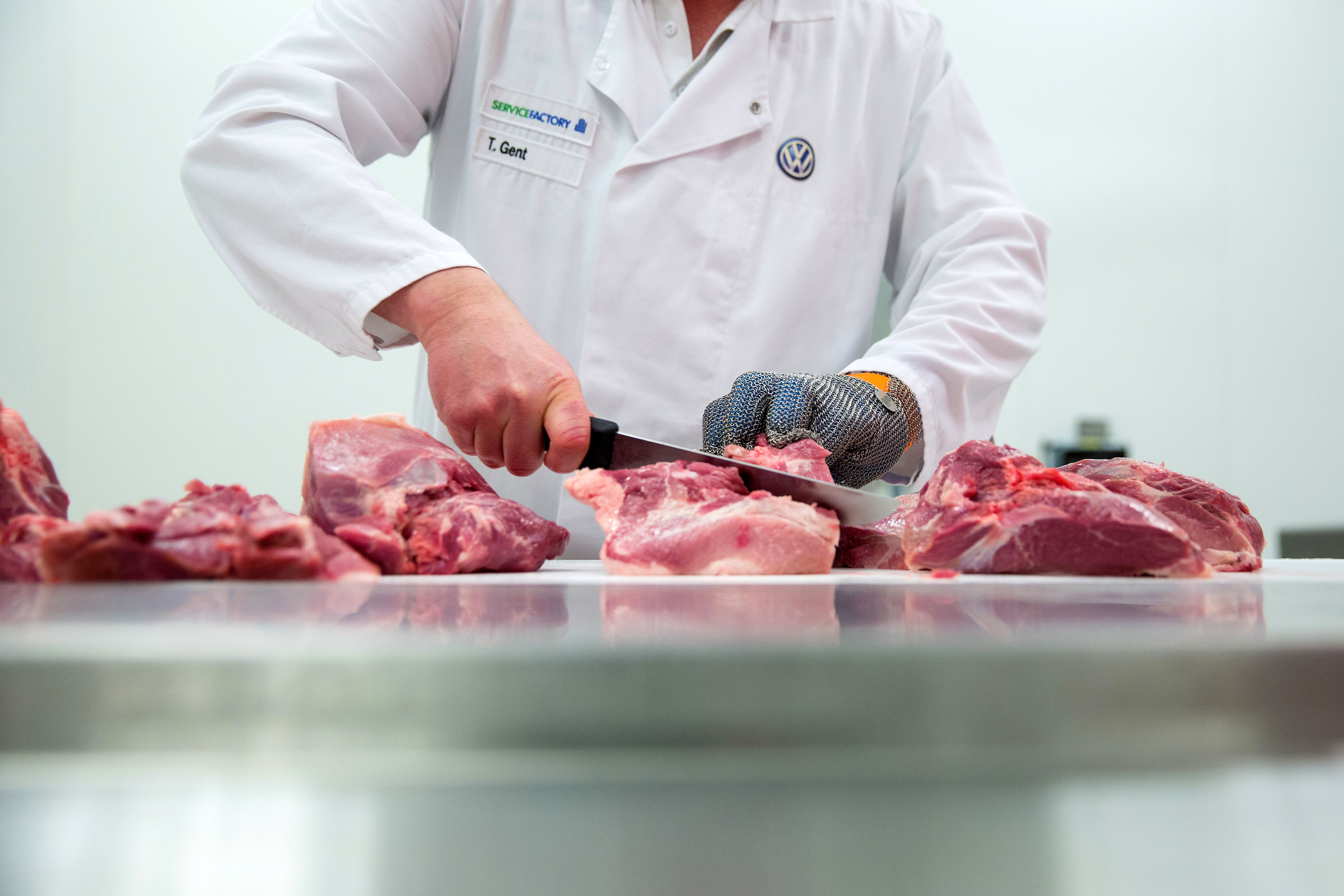 A butcher slices cuts of pork at the currywurst sausage production line in the Volkswagen AG (VW) manufacturing plant in Wolfsburg, Germany.