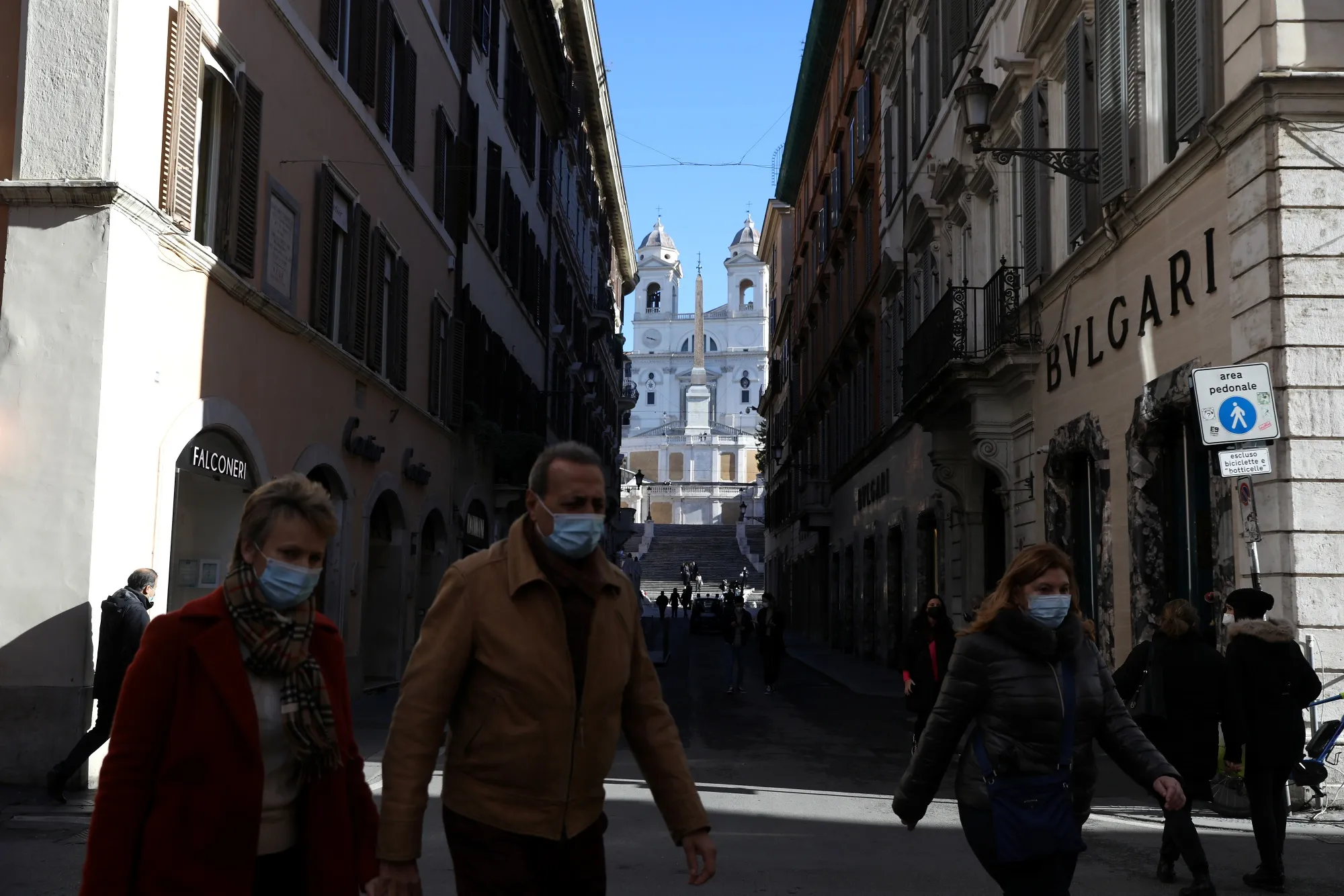 Pedestrians walk along Via Condotti, in view of the Spanish Steps, in Rome.