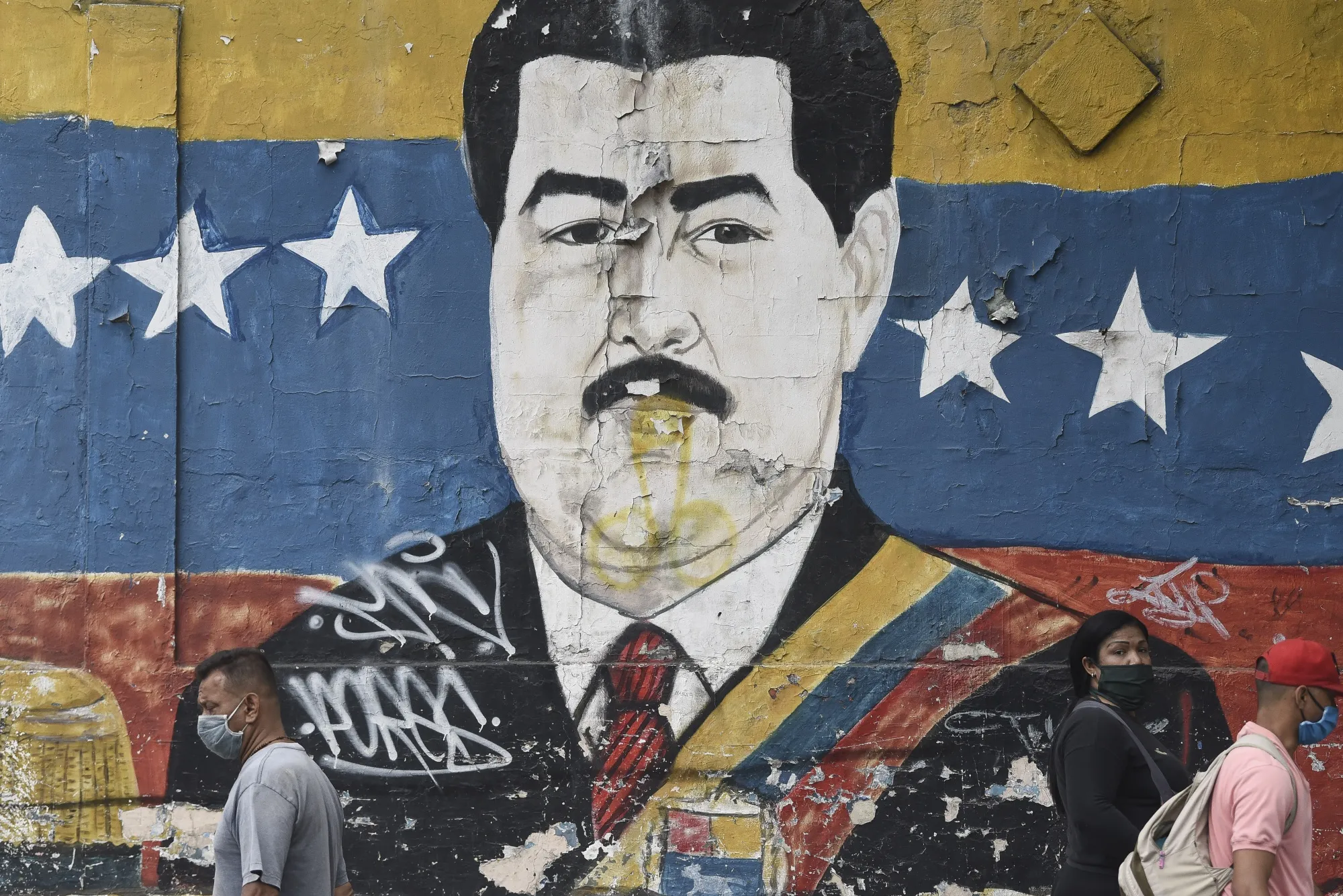 Pedestrians pass a mural of Nicolas Maduro in the Petare neighborhood of Caracas.