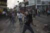 A demonstrator throws a rock at members of the Bolivarian National Guard.