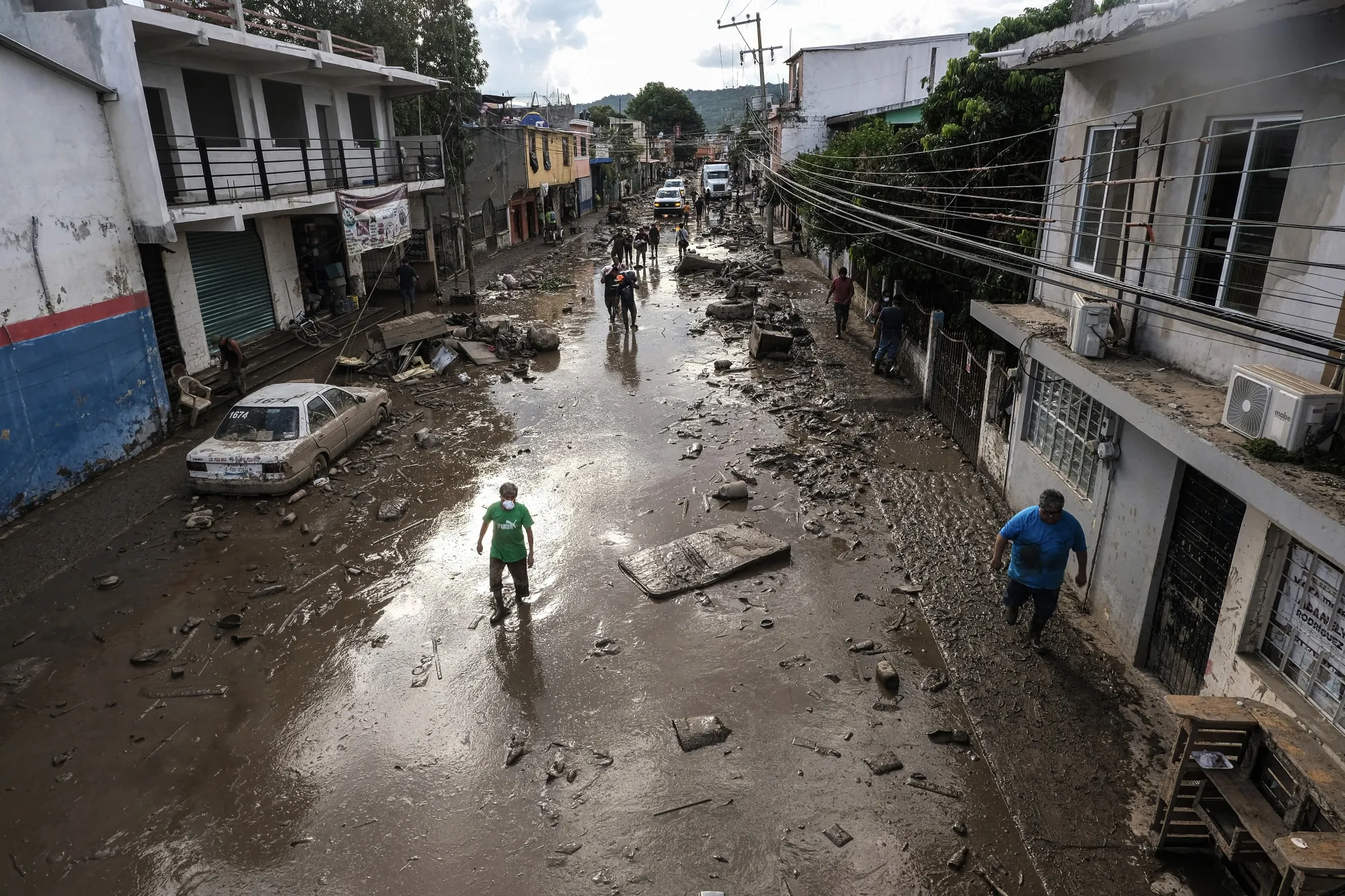 People walk on a street covered in mud and debris caused by heavy rains in the Las Granjas neighborhood in Poza Rica, Veracruz state, Mexico on Oct. 14.&nbsp;