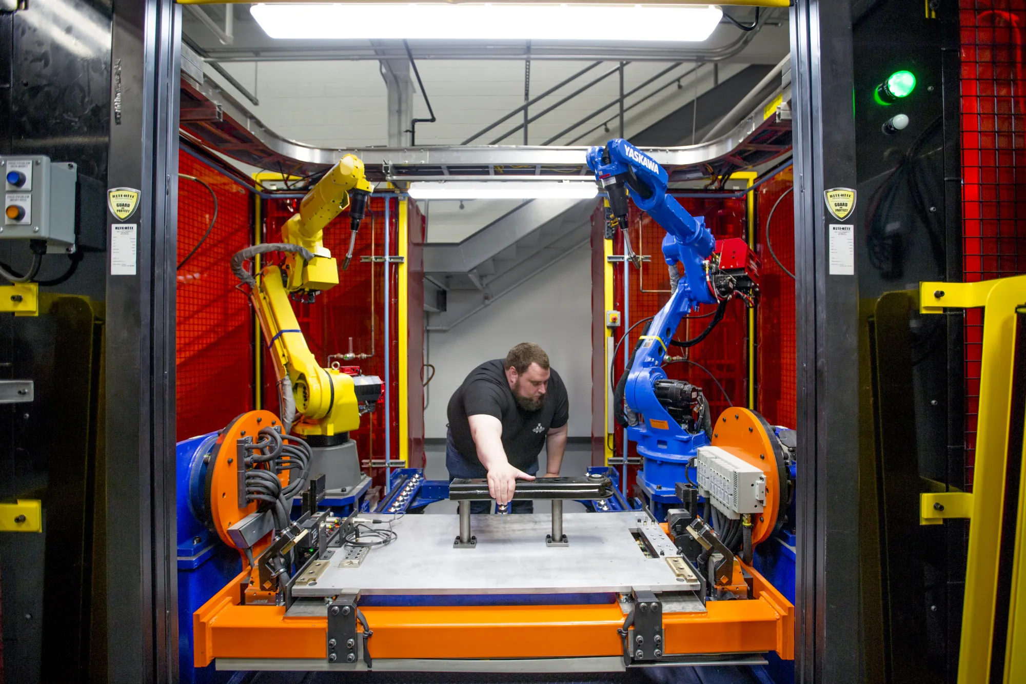 A worker adjusts a robotic MIG welding cell during the opening of the Martinrea International technical center.