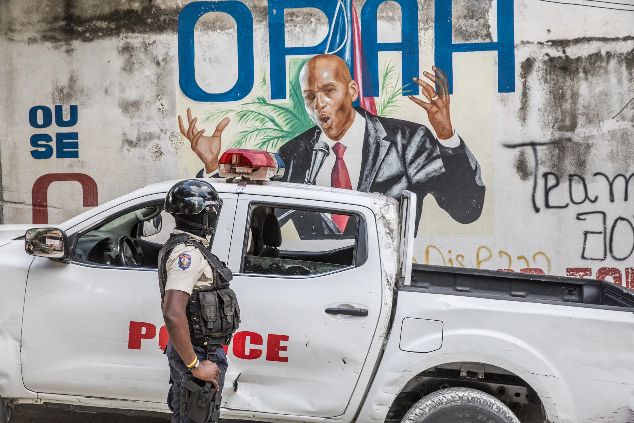 A police officer stands by a wall painted with a mural of late Haitian President Jovenel Moise after FBI agents and forensic teams conducted searches in his residence in Port-au-Prince on July 15.