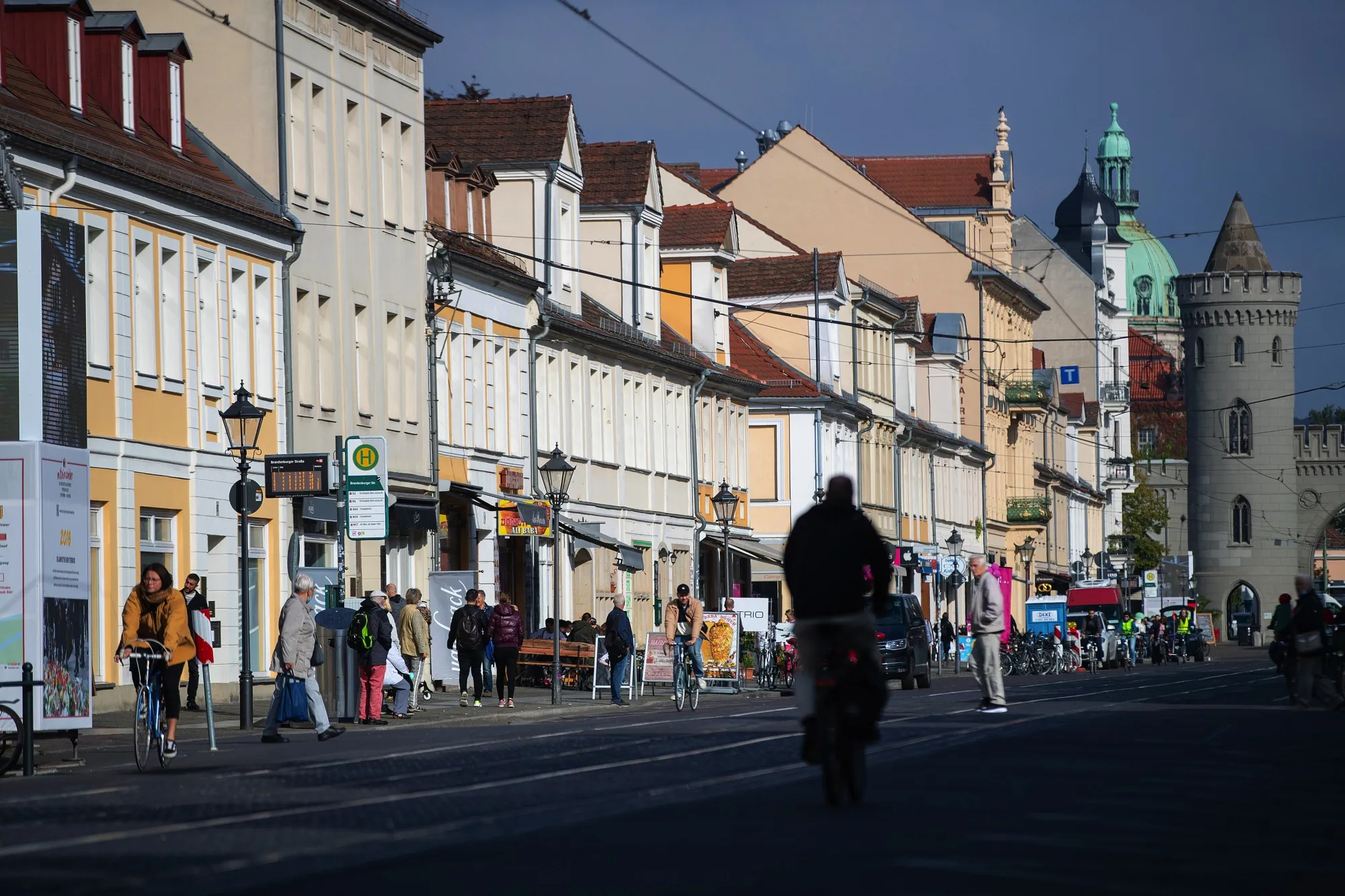 Pedestrians and cyclists pass tram lines and retail outlets in Potsdam.